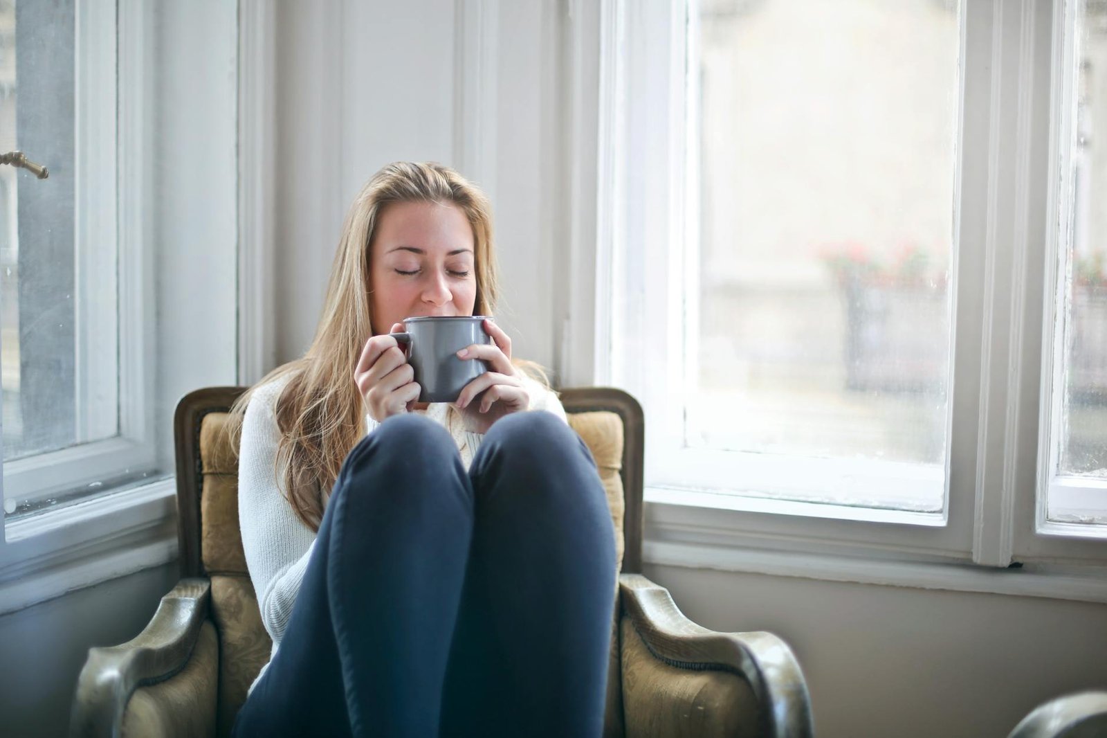 woman holding gray tea cup by drinking it