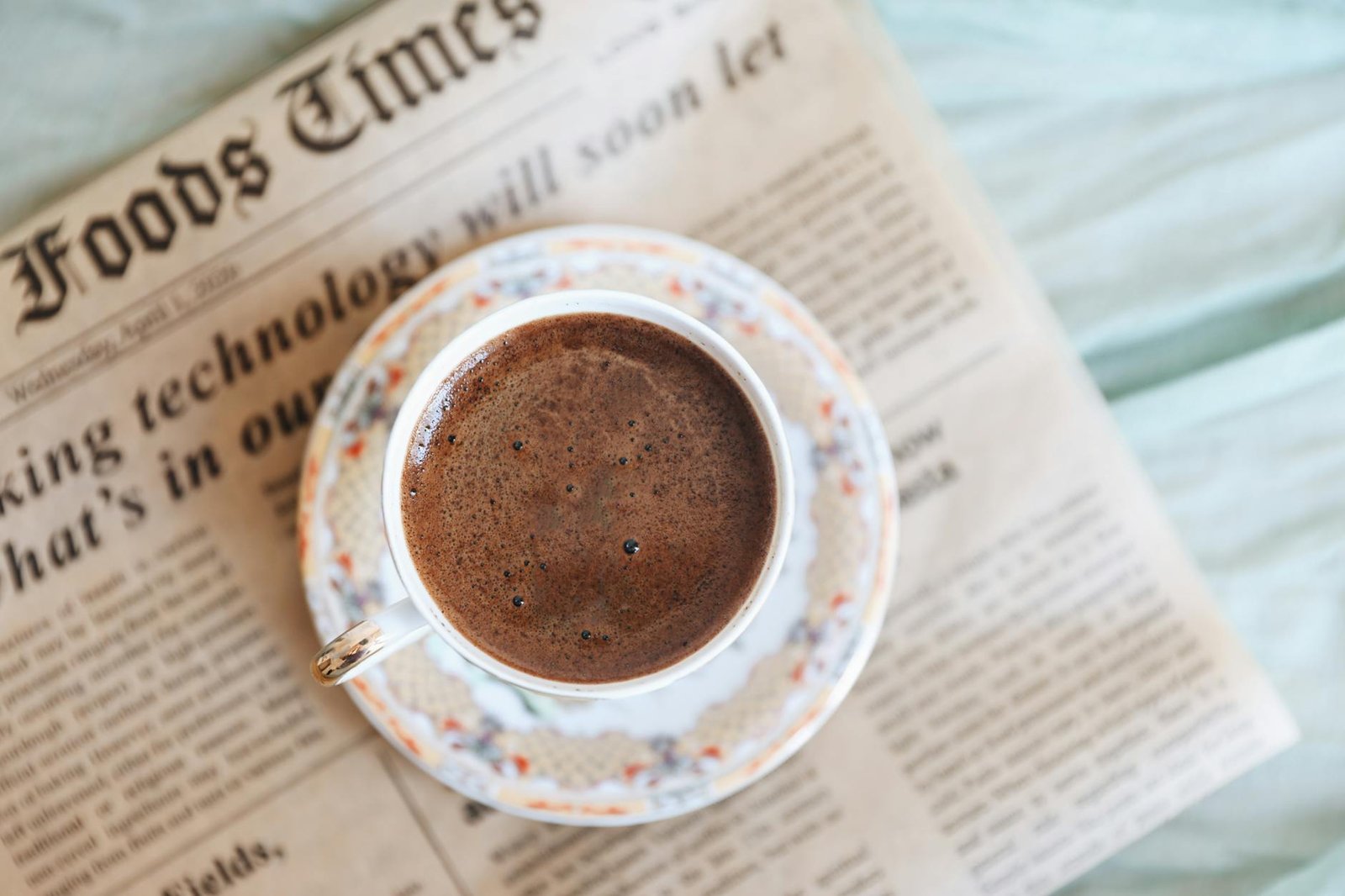 close up of a cup of coffee standing on a newspaper