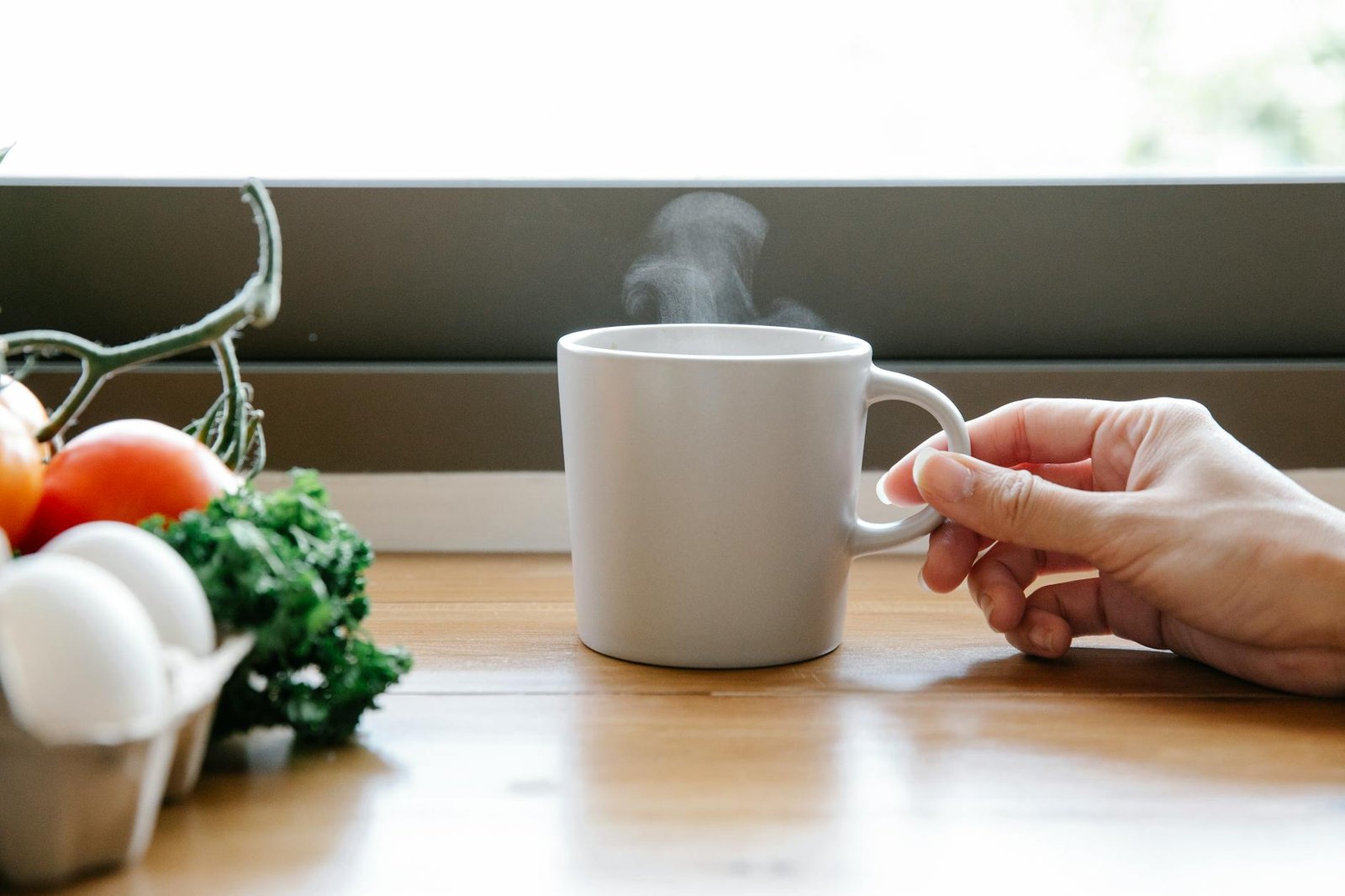 crop woman with cup of coffee on table